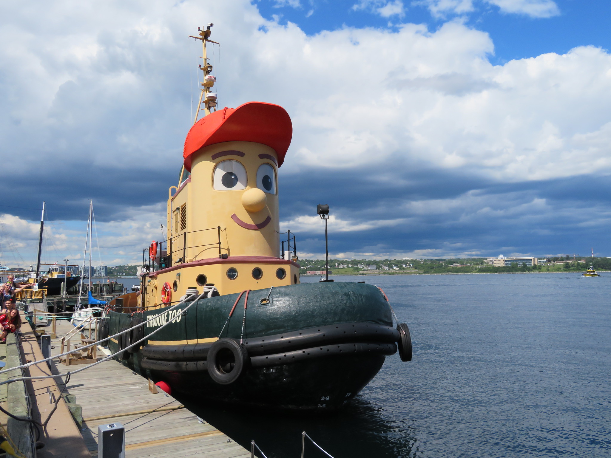 picture of a boat at a dock with a cartoon man's face and a red cap