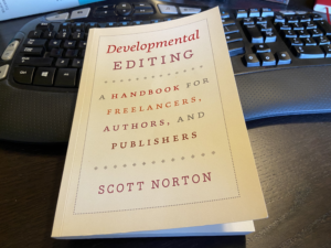 Cream colored cover of Developmental editing by Scott Norton sitting on a black computer keyboard